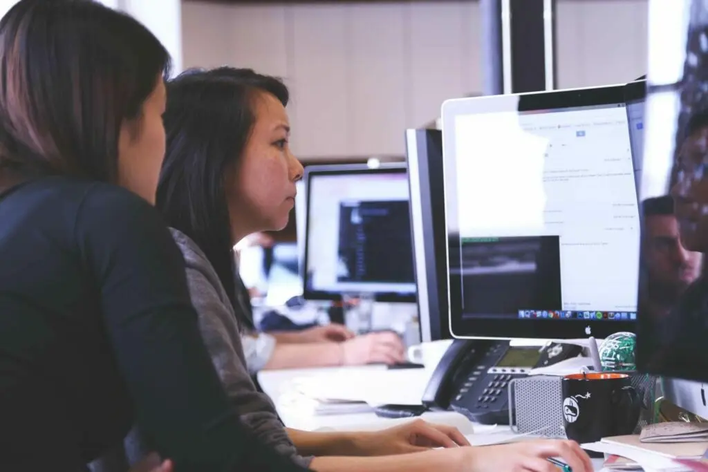 Two women looking at monitor discussing.
